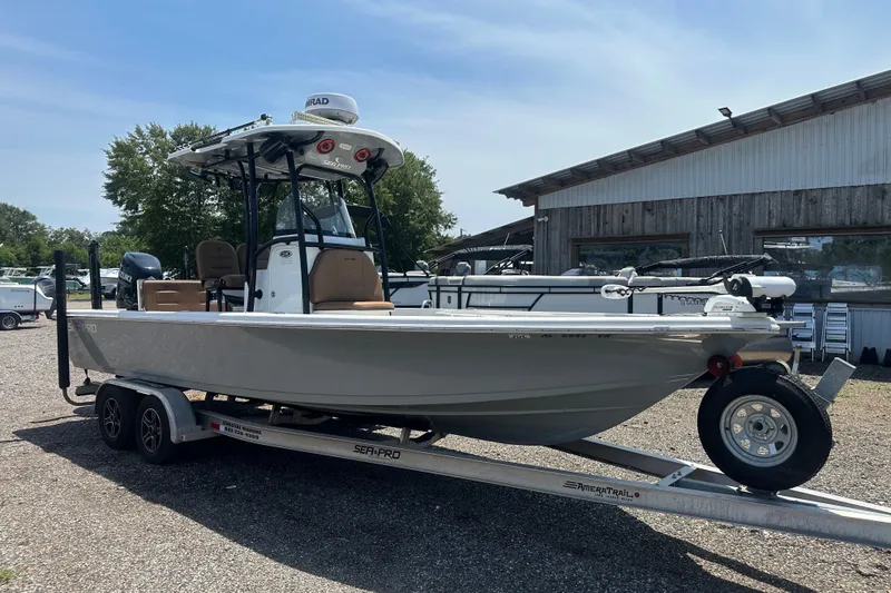 The Image of 2018 Sea Pro 248 Bay boat on trailer, parked outdoors near a rustic building. - 0