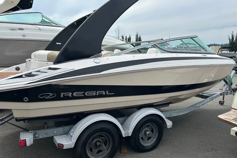The Image of 2011 Regal 2100 Bowrider boat on trailer, sleek design, parked outdoors. - 0