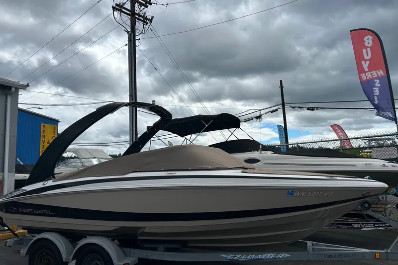 Slide: The Image of 2011 Regal 2100 Bowrider boat on trailer under cloudy sky at dealership. - 2