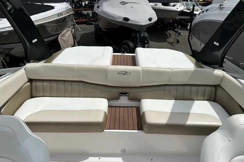 Slide: The Image of 2011 Regal 2100 Bowrider boat interior with beige seating and wood accents. - 10