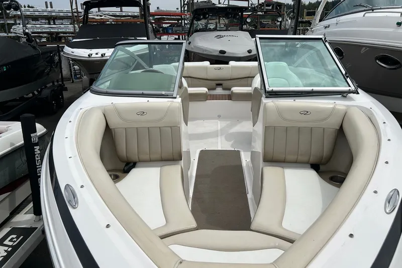 Slide: The Image of 2011 Regal 2100 Bowrider boat with spacious seating, docked among other boats. - 3
