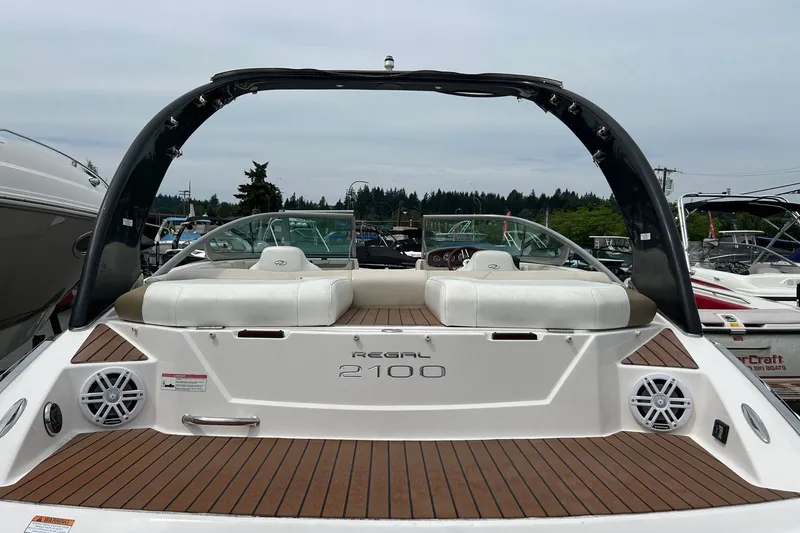 Slide: The Image of 2011 Regal 2100 Bowrider boat with white seating and wood deck, docked in marina. - 13