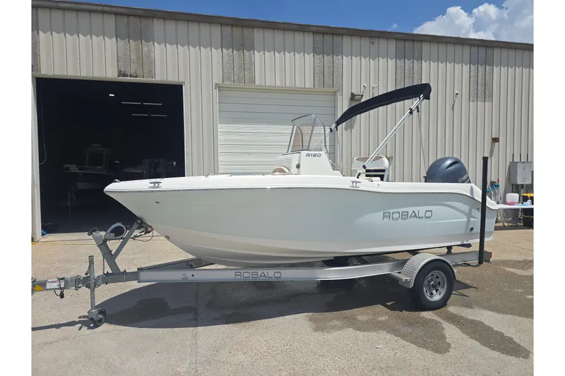 Slide: The Image of 2018 Robalo R180 Center Console boat on trailer outside a warehouse. - 13