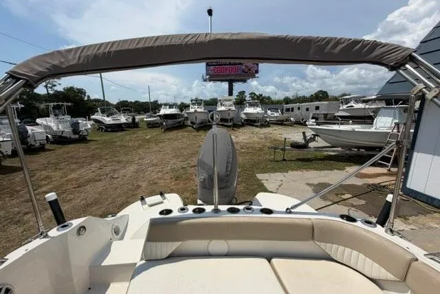 Slide: The Image of 2018 Stingray 212 SC boat with canopy, parked in a lot with other boats. - 21