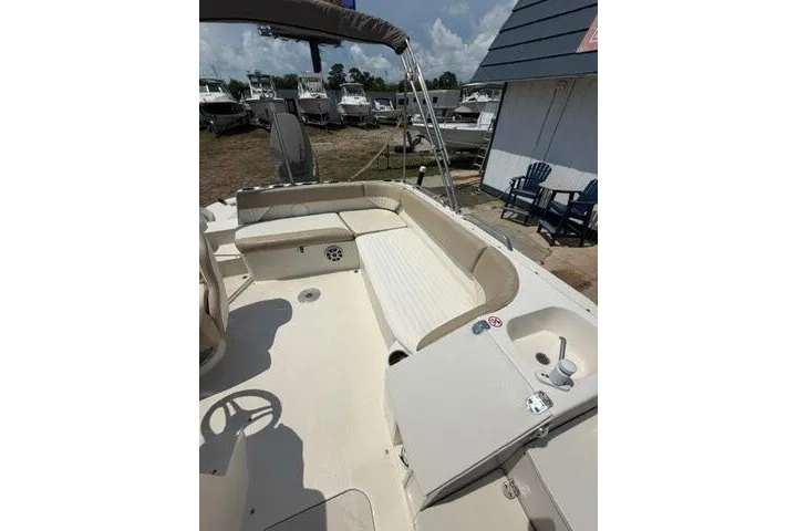 Slide: The Image of 2018 Stingray 212 SC boat with spacious seating, docked outdoors under a cloudy sky. - 18
