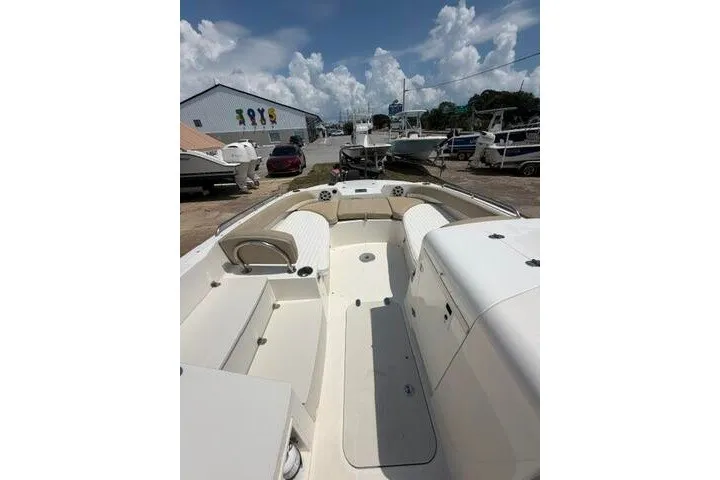 Slide: The Image of 2018 Stingray 212 SC boat interior with seating, parked outdoors under a cloudy sky. - 25
