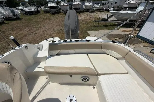 Slide: The Image of 2018 Stingray 212 SC boat interior with beige seating, docked among other boats. - 20