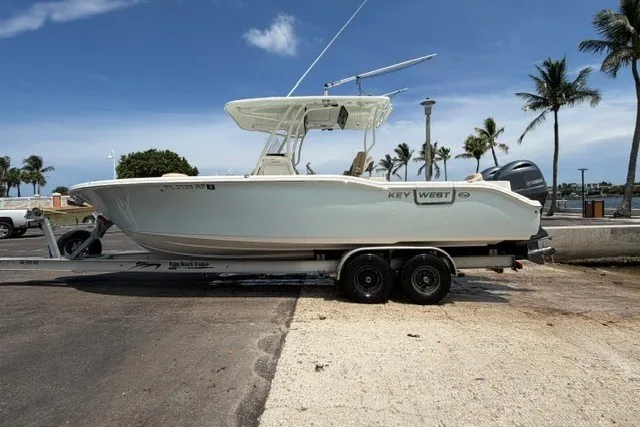 Slide: The Image of 2018 Key West 263 FS boat on trailer, parked near palm trees and waterfront. - 13