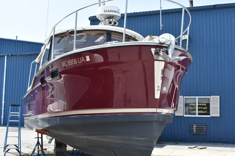 Slide: The Image of 2019 Ranger Tugs R-27 boat with maroon hull, docked near blue building. - 2