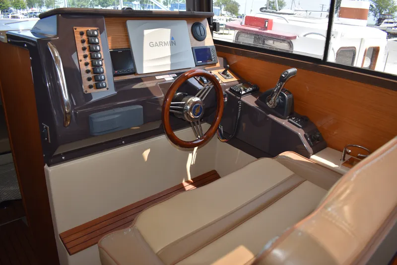Slide: The Image of 2019 Ranger Tugs R-27 helm with Garmin navigation, wood accents, and leather seating. - 34