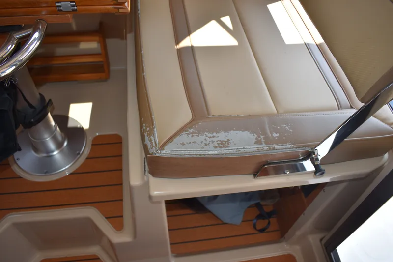 Slide: The Image of 2019 Ranger Tugs R-27 interior with worn beige seating and polished metal fixtures. - 31