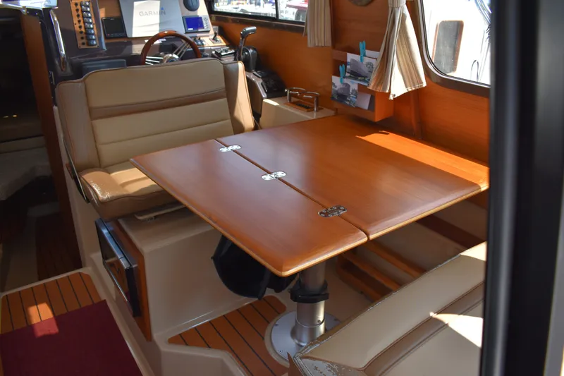 Slide: The Image of 2019 Ranger Tugs R-27 interior with wooden table and beige seating. - 29
