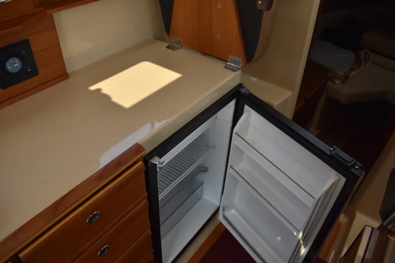 Slide: The Image of 2019 Ranger Tugs R-27 interior with open refrigerator and wooden cabinetry. - 45