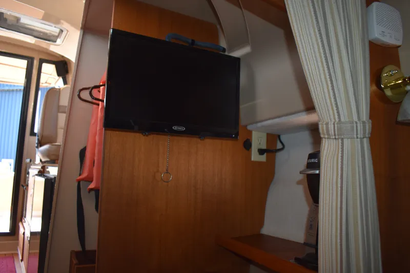 Slide: The Image of Interior of a 2019 Ranger Tugs R-27 boat featuring a mounted TV and striped curtain. - 43