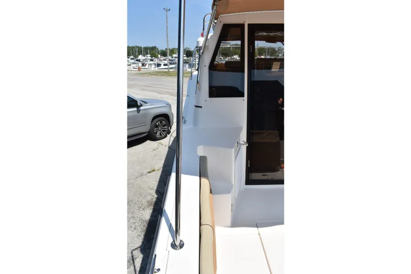 Slide: The Image of 2019 Ranger Tugs R-27 boat docked, side view with visible seating and railing. - 12