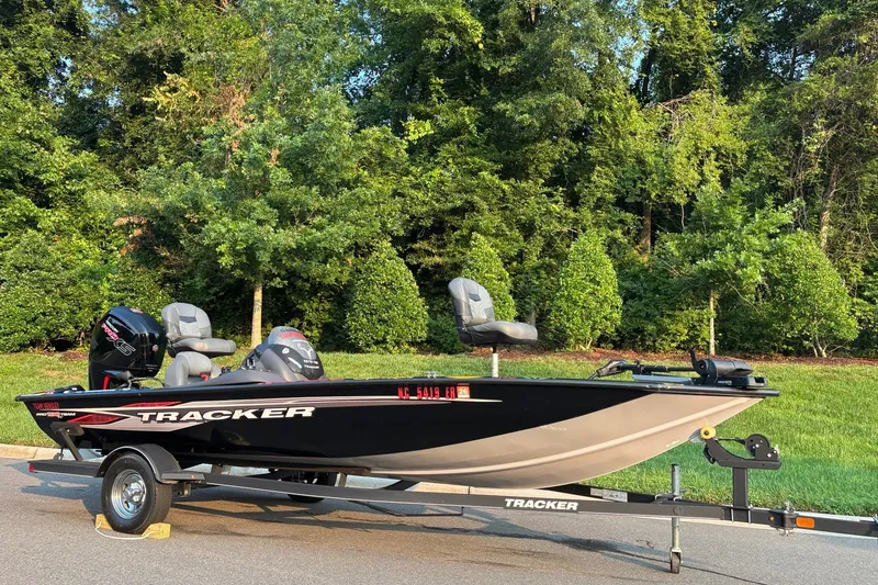 Slide: The Image of 2020 Tracker Pro Team 190 TX boat on trailer, parked near lush green trees. - 14