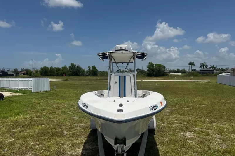 Slide: The Image of 2007 Contender 23 Open boat on trailer, parked on grassy field under blue sky. - 1