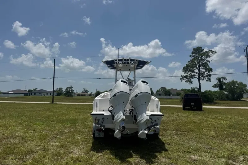 Slide: The Image of 2007 Contender 23 Open boat with dual outboard motors on grassy field under blue sky. - 2