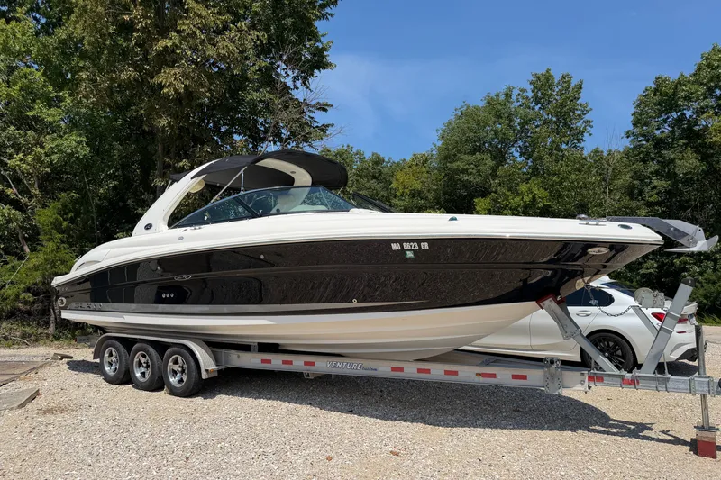 The Image of 2008 Sea Ray 290 SLX boat on trailer, parked outdoors with trees in background. - 0