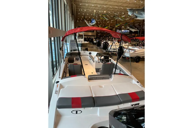 Slide: The Image of 2027 Tahoe T21 boat with red canopy displayed in a showroom. - 5