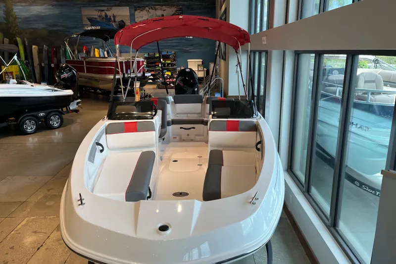 Slide: The Image of 2027 Tahoe T21 boat with red canopy displayed in showroom. - 2