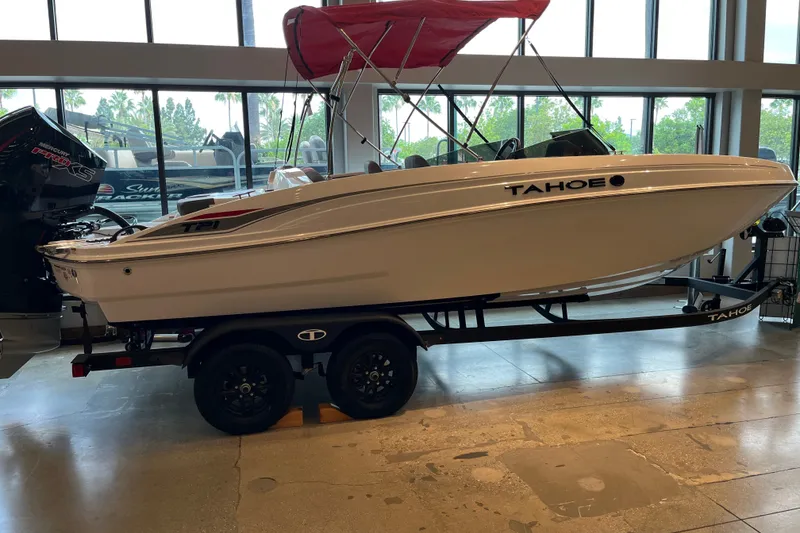 The Image of 2027 Tahoe T21 boat with red canopy on trailer in showroom. - 0