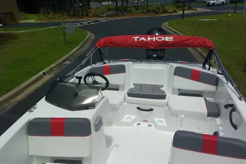 Slide: The Image of 2027 Tahoe T18 boat interior with red and gray seating, steering wheel, and canopy. - 2