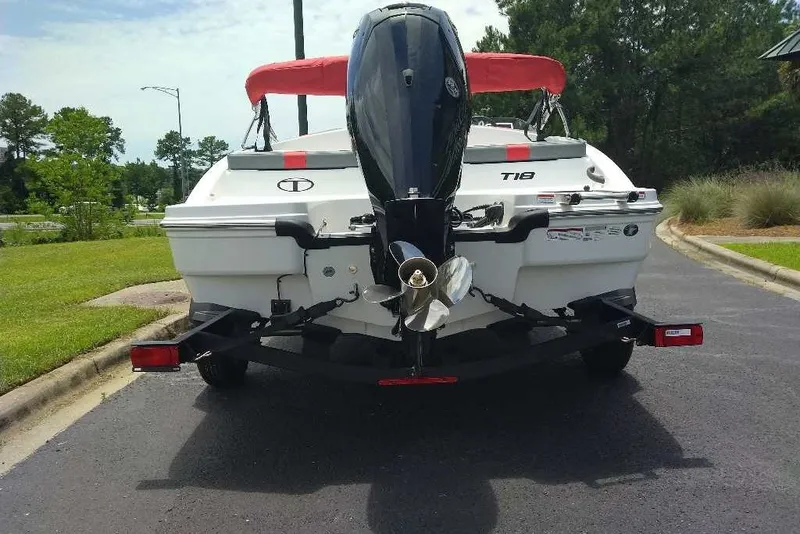 Slide: The Image of 2027 Tahoe T18 boat on trailer, rear view with outboard motor, parked on asphalt. - 6