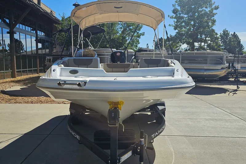 Slide: The Image of 2027 Tahoe 1950 boat with canopy on trailer, parked outdoors in sunny setting. - 2