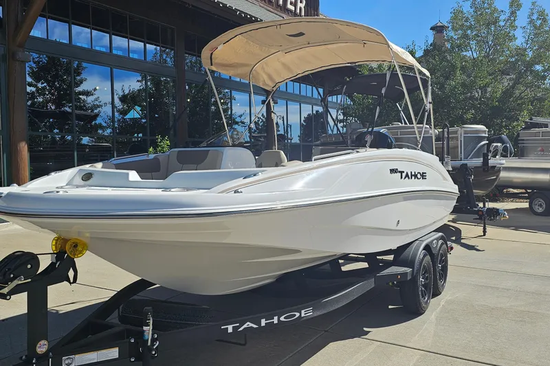 Slide: The Image of 2027 Tahoe 1950 boat with canopy on trailer, parked outdoors. - 1