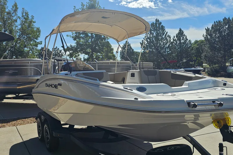 Slide: The Image of 2027 Tahoe 1950 boat with canopy on trailer, parked outdoors under clear sky. - 3