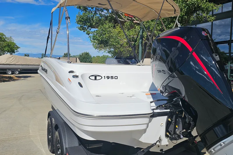 Slide: The Image of 2027 Tahoe 1950 boat with outboard motor, parked on a trailer under a clear sky. - 7
