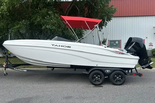 Slide: The Image of 2027 Tahoe T21 boat with red canopy on trailer, parked outdoors. - 1