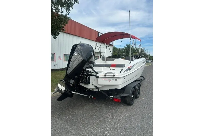Slide: The Image of 2027 Tahoe T21 boat with red canopy on trailer, parked near a building. - 6