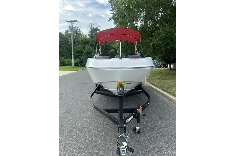 Slide: The Image of 2027 Tahoe T21 boat with red canopy on trailer, parked on a road. - 2