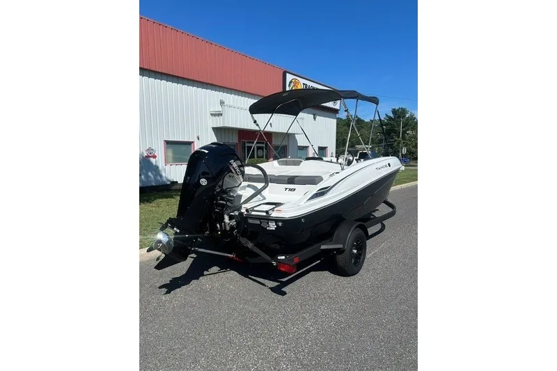 Slide: The Image of 2027 Tahoe T18 boat on trailer, parked outside a building under clear blue sky. - 6