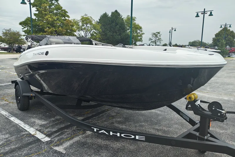 Slide: The Image of 2027 Tahoe T18 boat on trailer in parking lot, surrounded by trees and lampposts. - 2