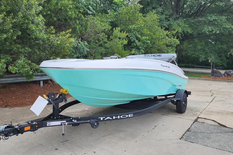 Slide: The Image of 2027 Tahoe T18 boat on trailer, parked outdoors, surrounded by lush greenery. - 1