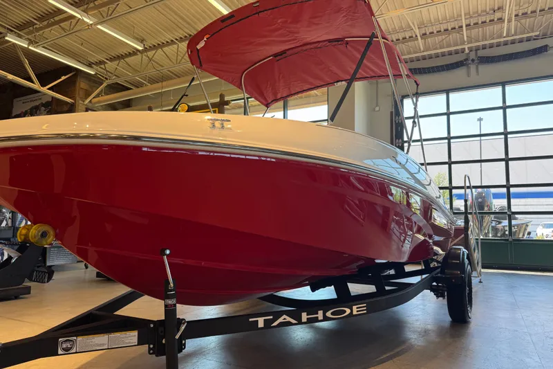 Slide: The Image of Red 2027 Tahoe T16 boat with canopy displayed indoors on a trailer. - 59