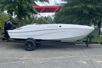 Slide: The Image of 2027 Tahoe T18 boat with red canopy on trailer, parked outdoors. - 6