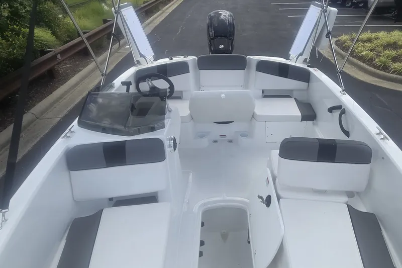 Slide: The Image of 2027 Tahoe T18 boat interior with seating and steering wheel, parked on pavement. - 2