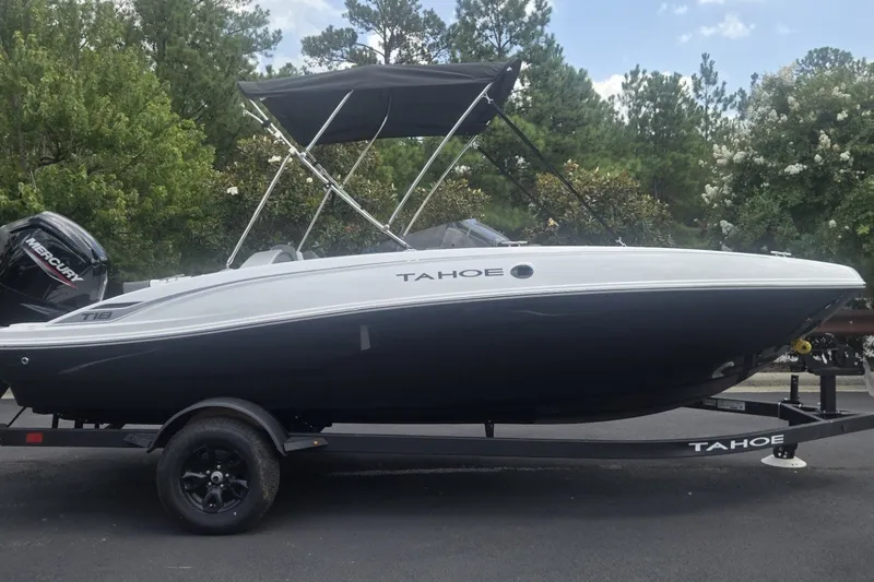 The Image of 2027 Tahoe T18 boat on trailer, parked outdoors with trees in background. - 0