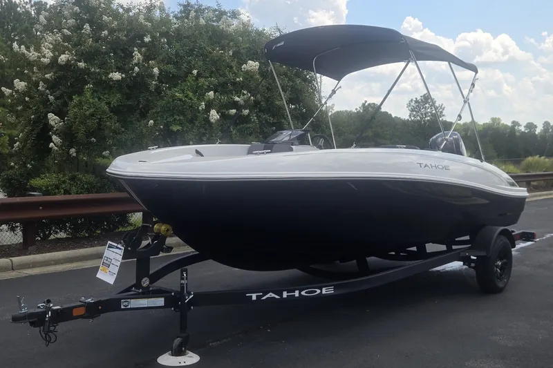 Slide: The Image of 2027 Tahoe T18 boat on trailer, parked outdoors with trees in background. - 1