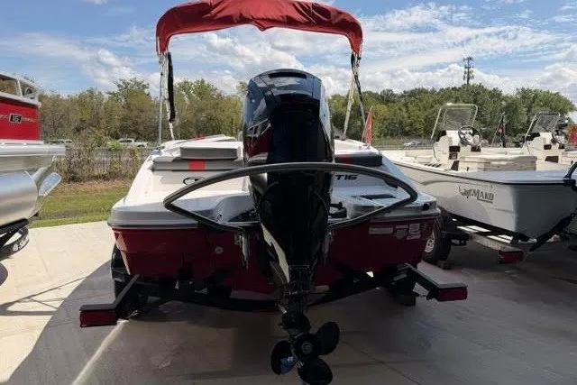 Slide: The Image of 2027 Tahoe T16 boat with red canopy and outboard motor, parked on a sunny day. - 2