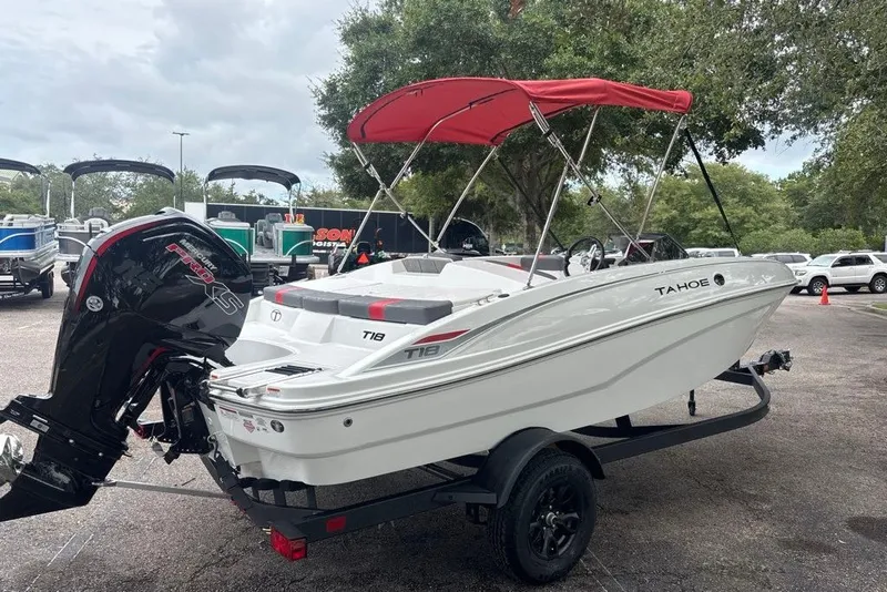 Slide: The Image of 2027 Tahoe T18 boat with red canopy on trailer in parking lot. - 3