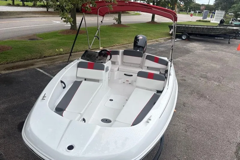 Slide: The Image of 2027 Tahoe T18 boat with red canopy, parked on pavement near green grass. - 6