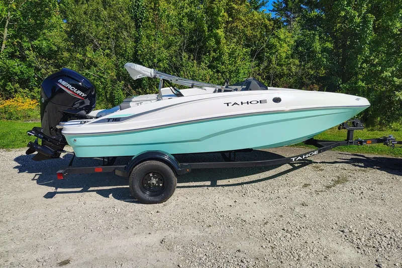 The Image of 2027 Tahoe T16 boat on trailer, parked outdoors with lush greenery background. - 0