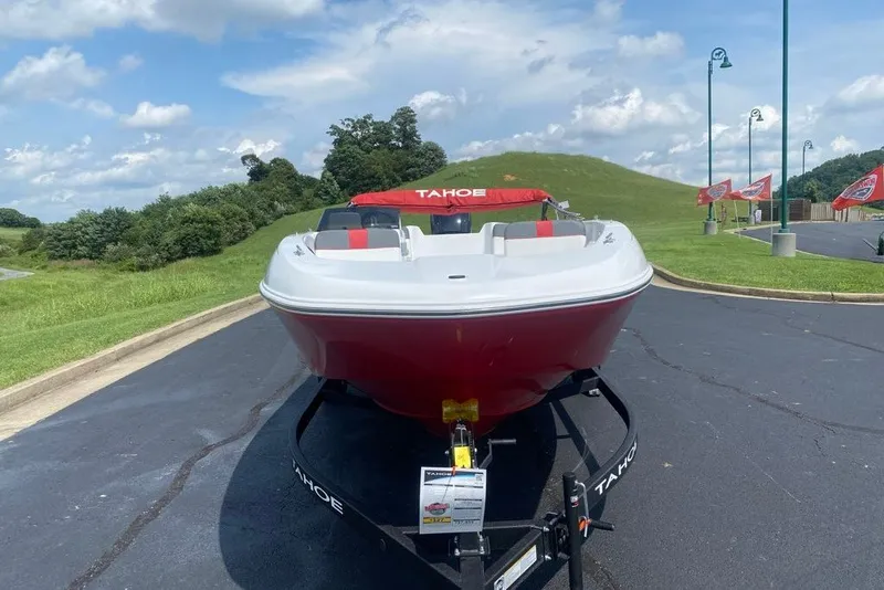 Slide: The Image of 2027 Tahoe T18 boat on trailer, parked on asphalt, with grassy hills and blue sky background. - 3