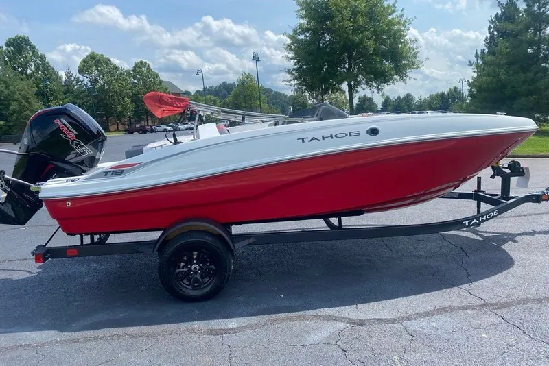 The Image of 2027 Tahoe T18 boat with red hull on trailer, parked outdoors. - 0