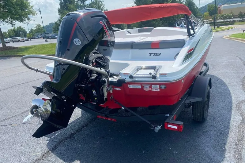 Slide: The Image of 2027 Tahoe T18 boat with outboard motor, red and white design, parked on pavement. - 1